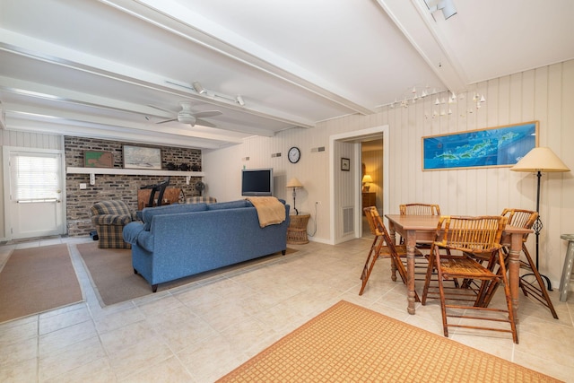 living area with a brick fireplace, ceiling fan, light tile patterned floors, and beamed ceiling