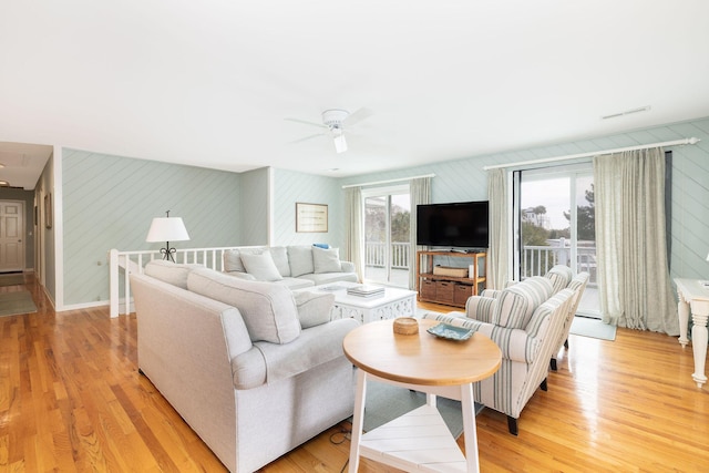 living area with light wood finished floors, baseboards, and a ceiling fan