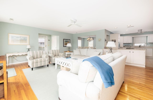 living room with ceiling fan with notable chandelier, light wood finished floors, visible vents, and recessed lighting