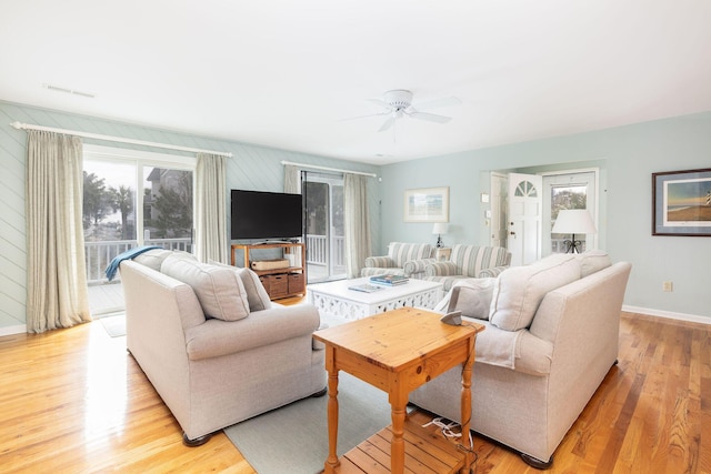 living room featuring a ceiling fan, visible vents, light wood-style flooring, and baseboards