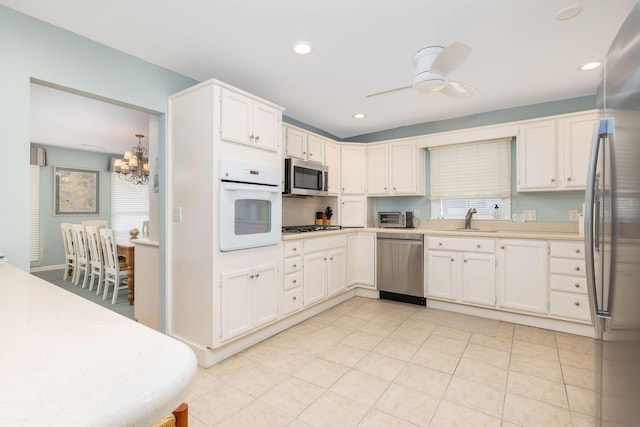 kitchen featuring a toaster, appliances with stainless steel finishes, ceiling fan with notable chandelier, light countertops, and recessed lighting