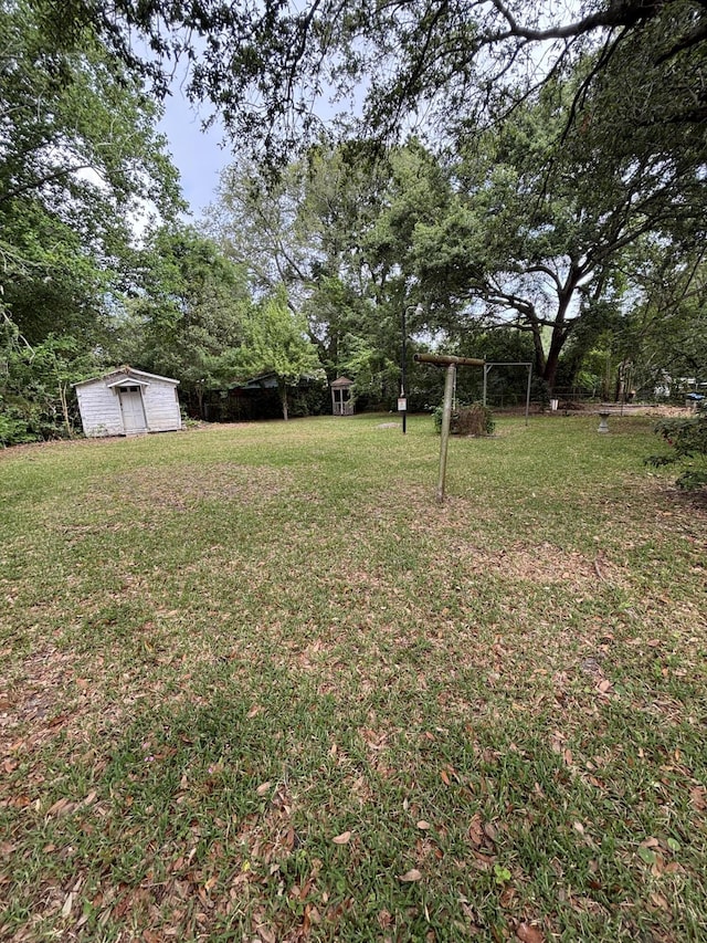 view of green lawn with a storage unit, an outbuilding, and view of scattered trees