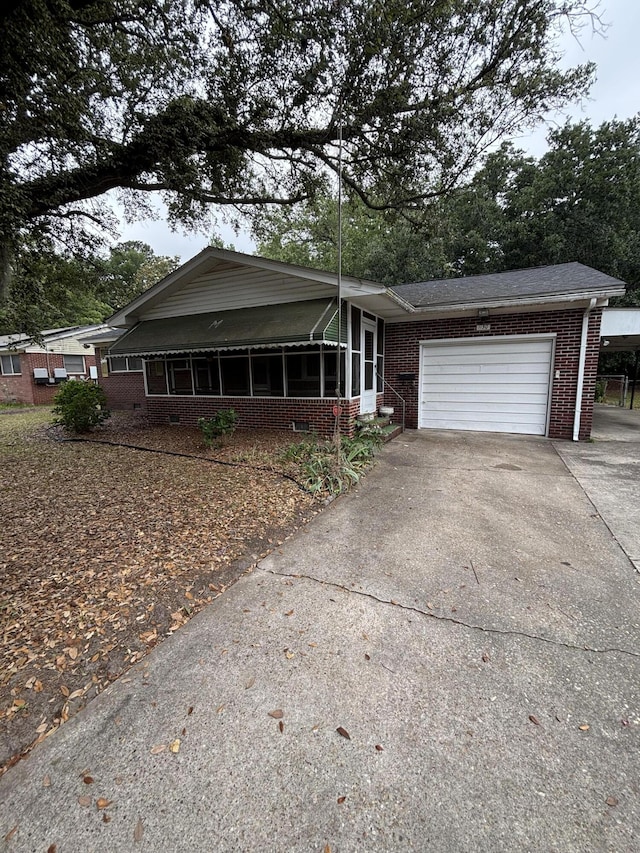 view of front facade featuring brick siding, a garage, concrete driveway, and a sunroom