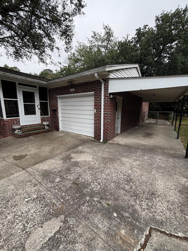 view of home's exterior with concrete driveway, brick siding, a garage, and an attached carport