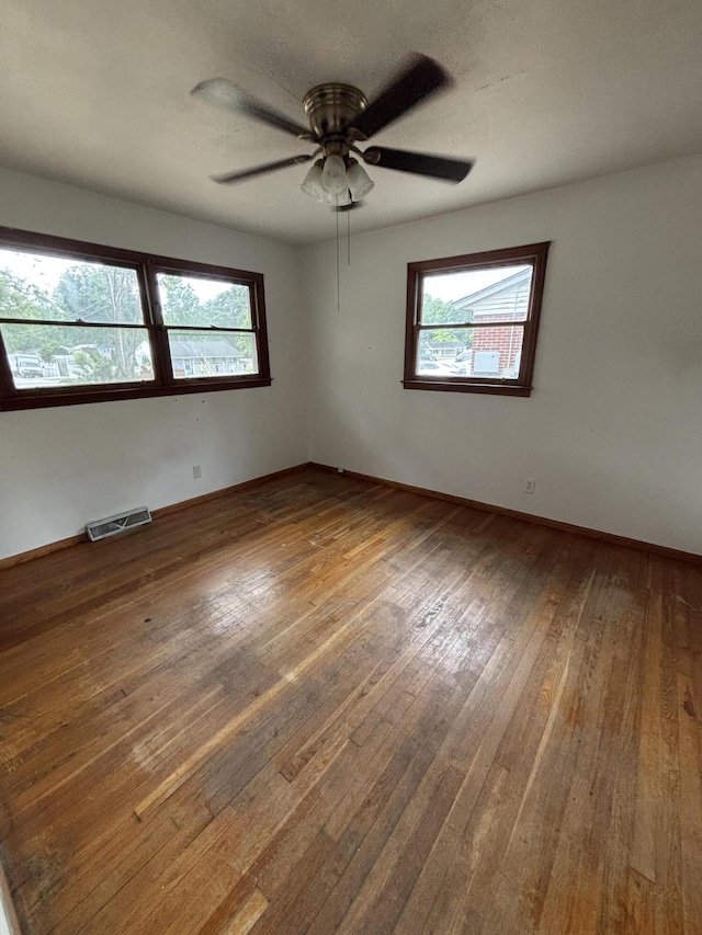 unfurnished room with hardwood / wood-style flooring, a ceiling fan, and baseboards