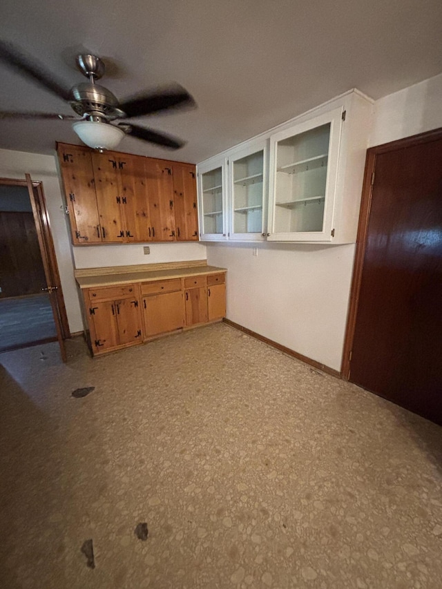 kitchen featuring ceiling fan, baseboards, and glass insert cabinets