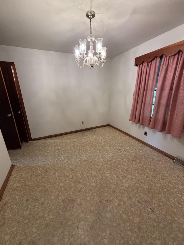 unfurnished room featuring a chandelier, baseboards, and carpet