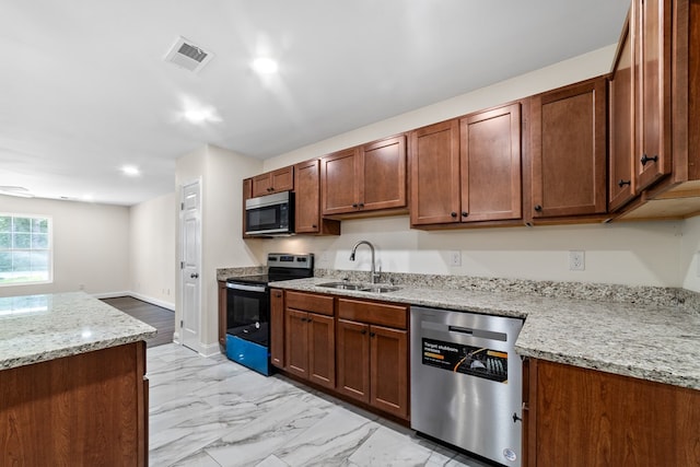 kitchen with light stone countertops, stainless steel appliances, and sink