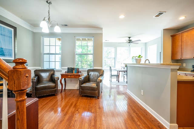 sitting room featuring ceiling fan with notable chandelier, light wood-type flooring, and ornamental molding