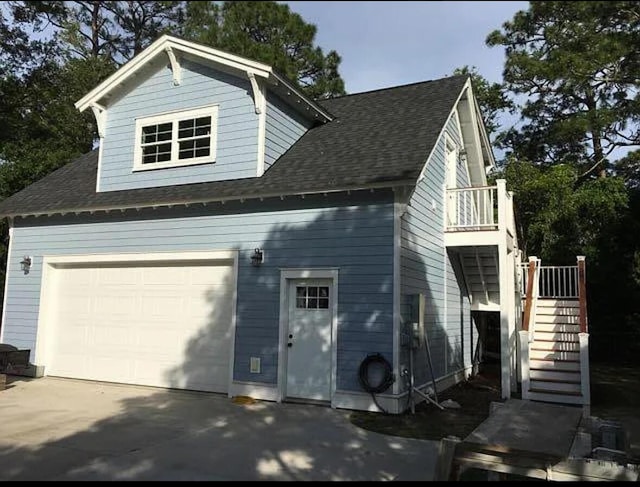 view of front of house with a garage, roof with shingles, and stairway