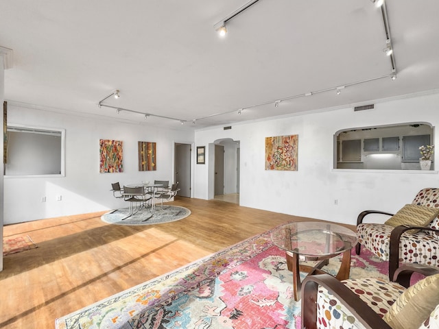 living room with arched walkways, visible vents, wood finished floors, and rail lighting