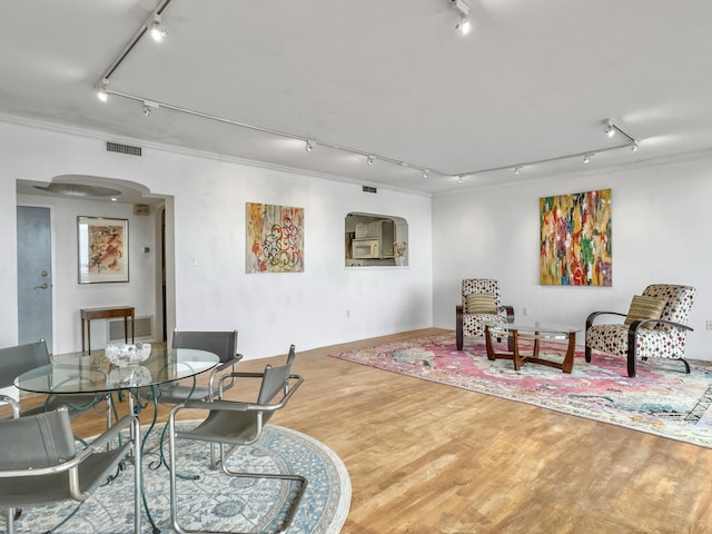 sitting room featuring arched walkways, wood finished floors, visible vents, and track lighting