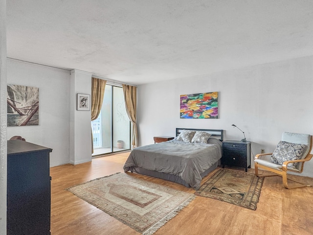 bedroom with expansive windows, a textured ceiling, and wood finished floors