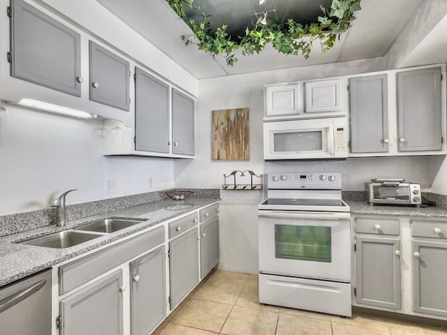 kitchen with white appliances, a sink, and gray cabinetry