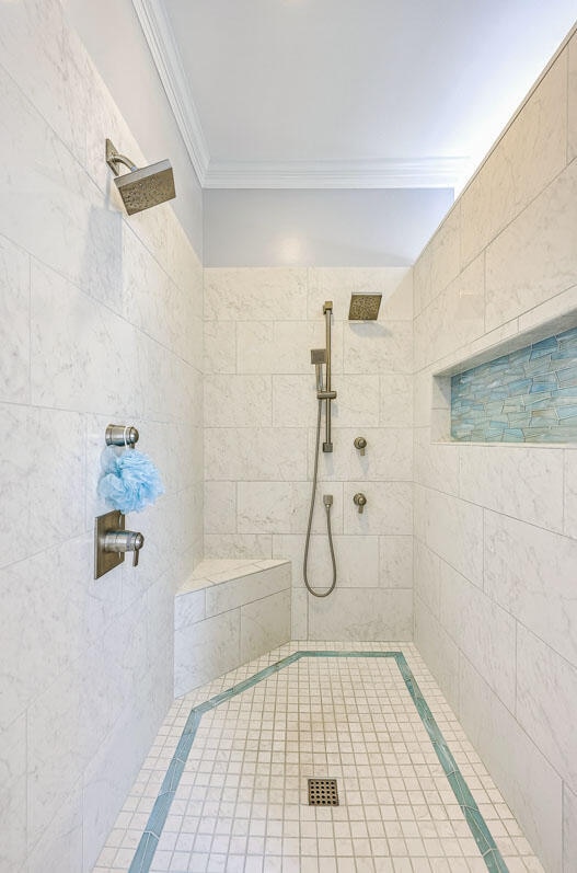 bathroom featuring a tile shower and crown molding