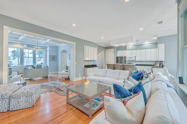 living room with crown molding and light wood-type flooring