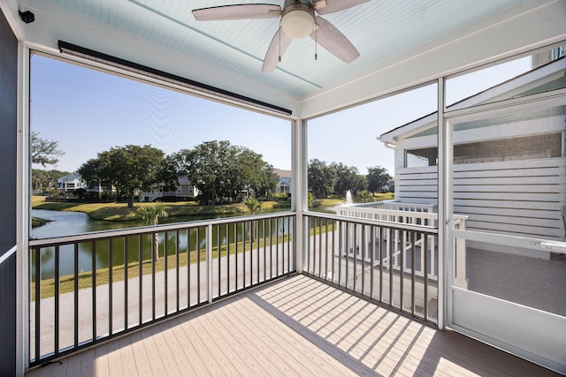 sunroom with ceiling fan and a water view