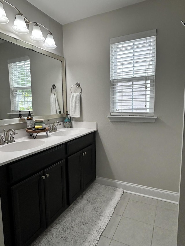bathroom featuring tile patterned flooring, double vanity, and baseboards