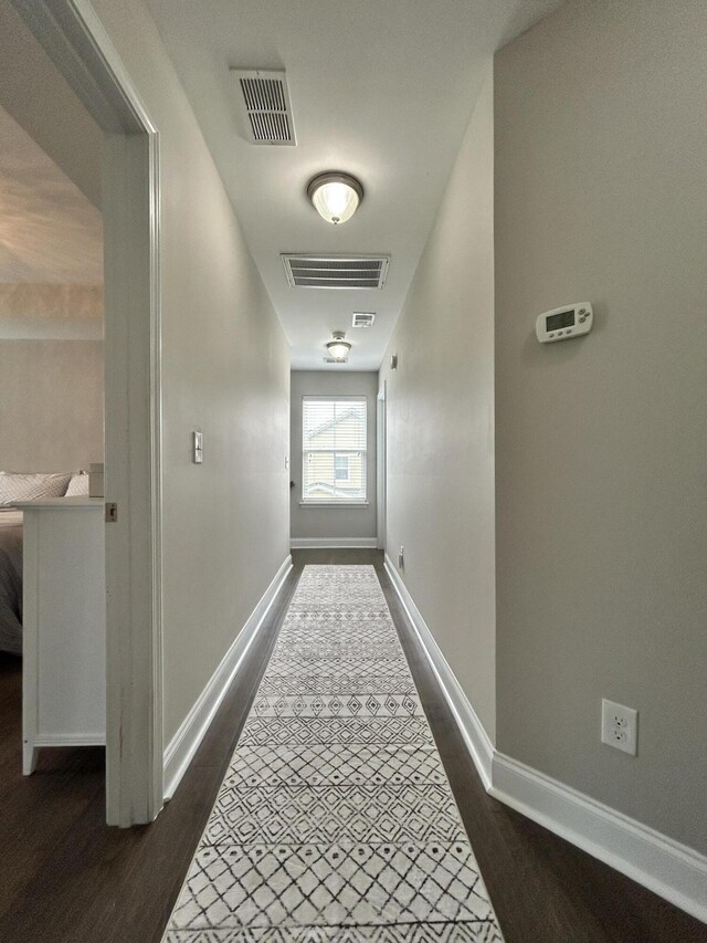 hallway featuring dark wood-style flooring and baseboards