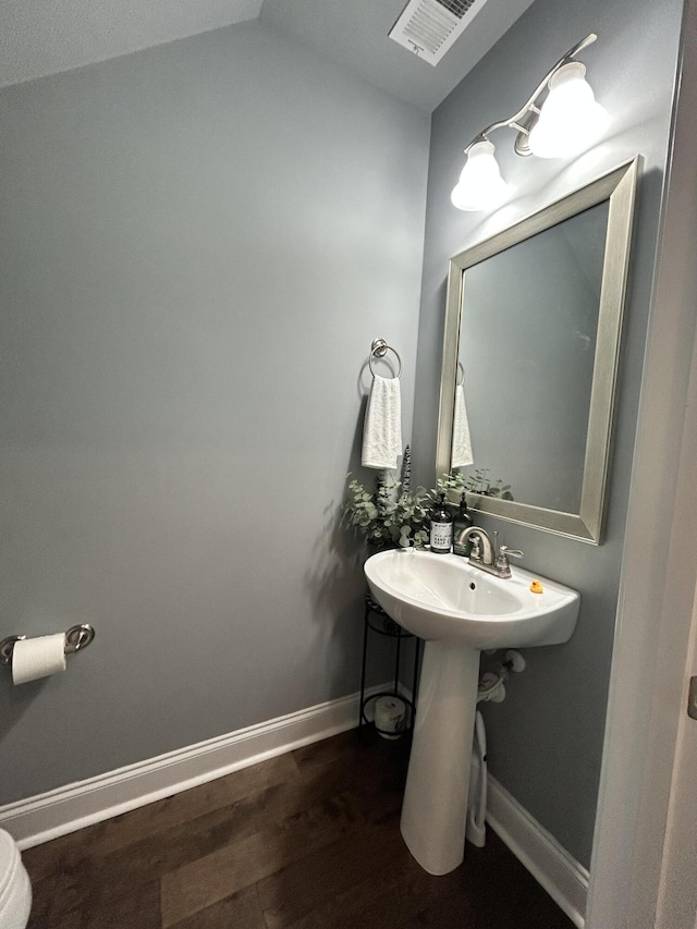 bathroom with wood finished floors, baseboards, vaulted ceiling, and a sink