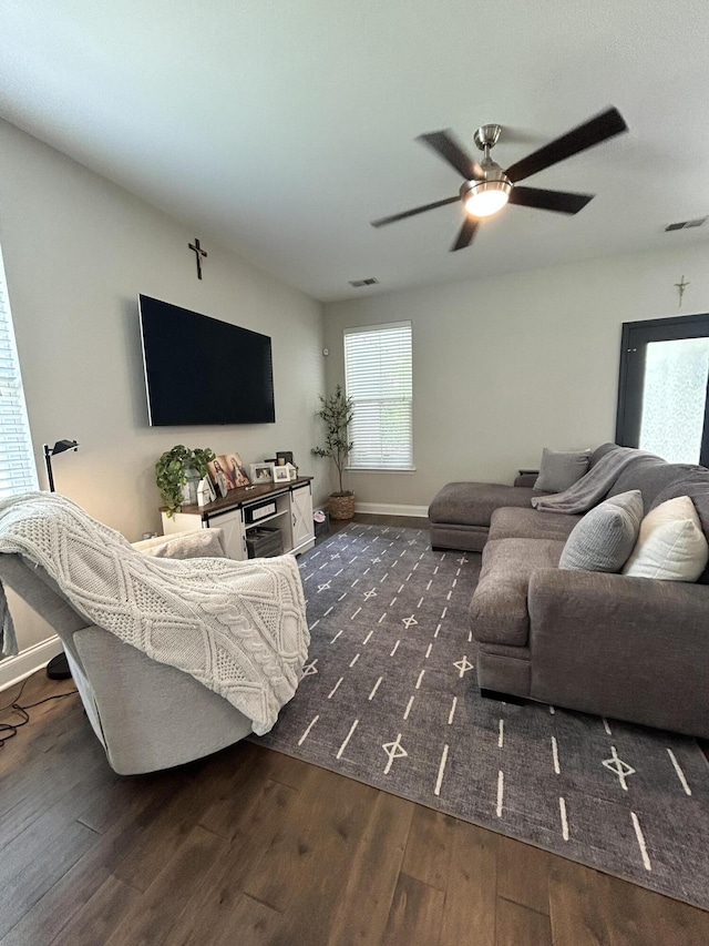 living area with dark wood-style flooring, a ceiling fan, and baseboards