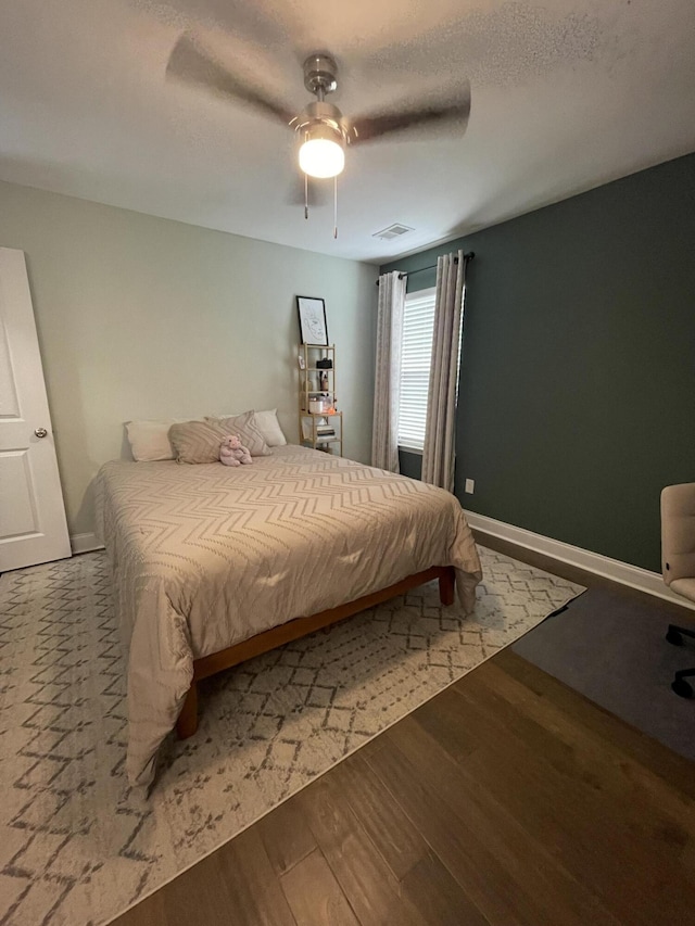 bedroom featuring wood finished floors, a ceiling fan, and baseboards