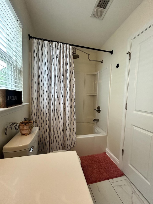 full bathroom with shower / tub combo with curtain, marble finish floors, and toilet