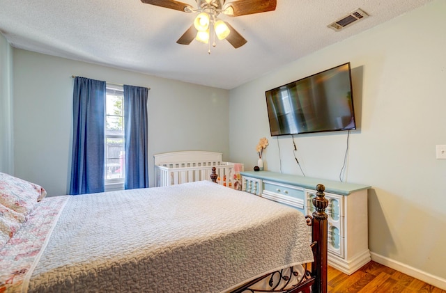 bedroom with hardwood / wood-style flooring, ceiling fan, and a textured ceiling