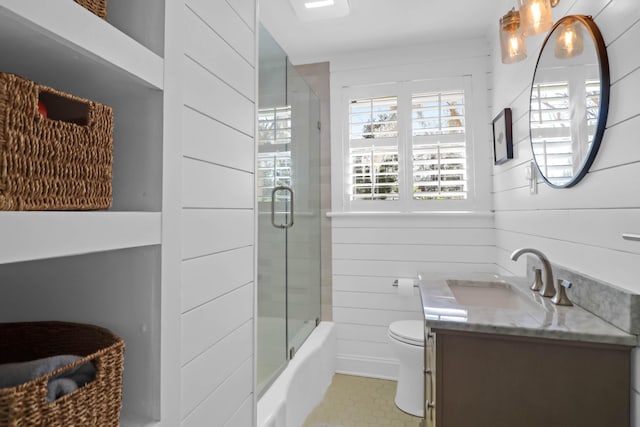 full bathroom with vanity, shower / bath combination with glass door, toilet, and wood walls