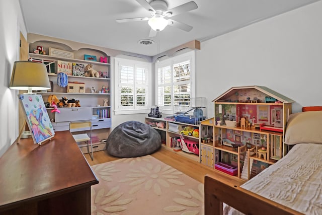 recreation room with a baseboard heating unit, hardwood / wood-style floors, and ceiling fan