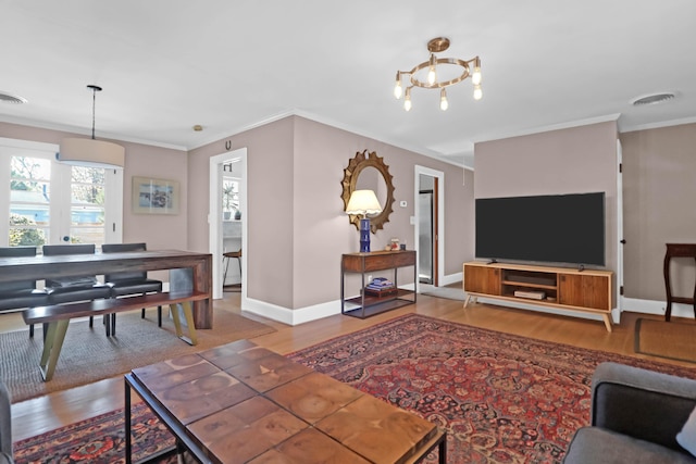 living room featuring hardwood / wood-style flooring, crown molding, and a chandelier