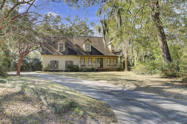 cape cod home with a porch and a front lawn