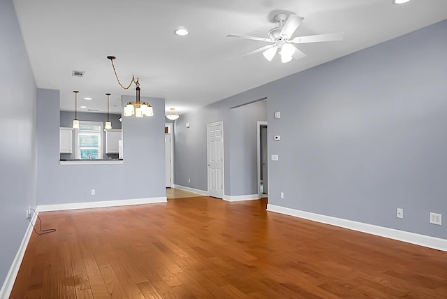 unfurnished living room featuring hardwood / wood-style flooring and ceiling fan with notable chandelier