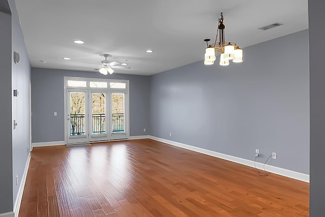 spare room featuring hardwood / wood-style flooring and ceiling fan with notable chandelier