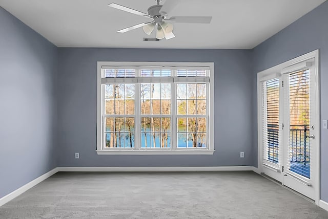 carpeted empty room with a wealth of natural light and ceiling fan