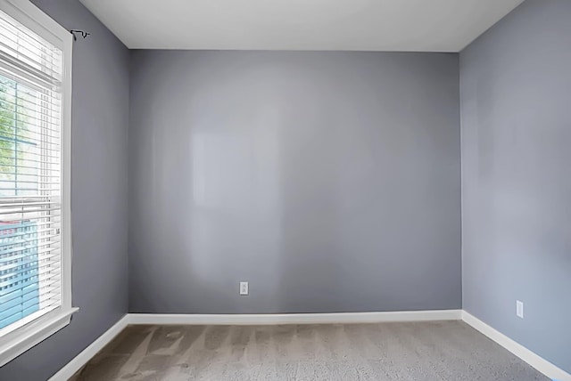 unfurnished room with light colored carpet and a wealth of natural light