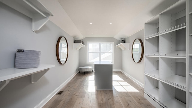 spacious closet featuring visible vents, vaulted ceiling, and light wood finished floors