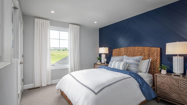 bedroom featuring light carpet, an accent wall, baseboards, and recessed lighting