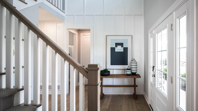 entrance foyer with stairway, a decorative wall, and wood finished floors