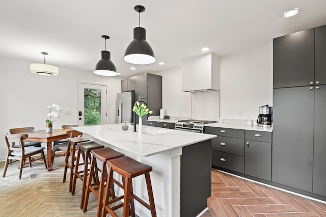 kitchen featuring sink, stainless steel appliances, an island with sink, decorative light fixtures, and custom exhaust hood