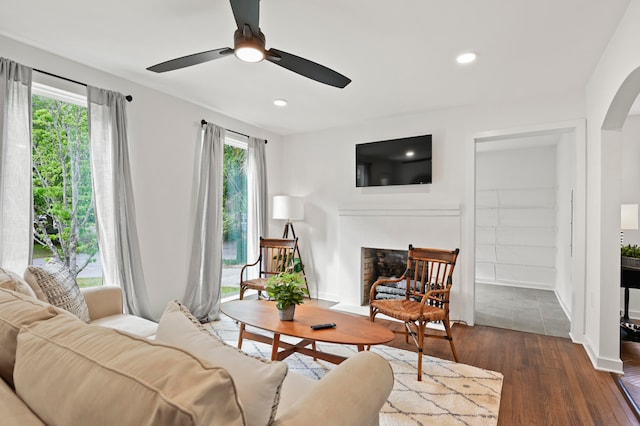 living room featuring ceiling fan, built in features, and dark wood-type flooring