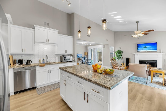 kitchen featuring a sink, light wood finished floors, dishwasher, and high vaulted ceiling