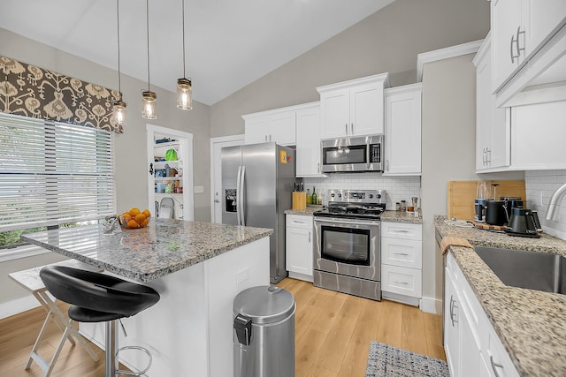 kitchen with a sink, light wood finished floors, backsplash, and stainless steel appliances