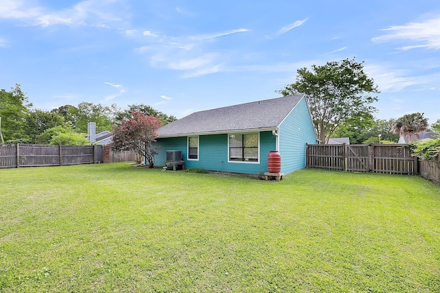 rear view of property with a fenced backyard, a shingled roof, and a yard