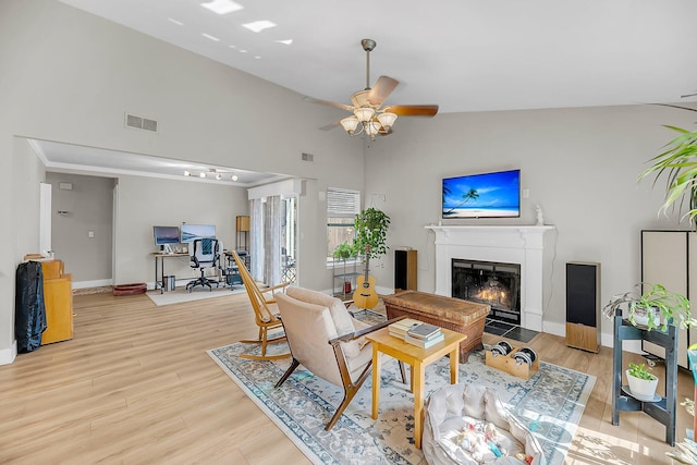 living room featuring a fireplace with flush hearth, ceiling fan, light wood finished floors, and visible vents