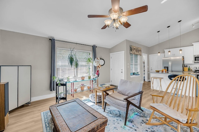 living area with a ceiling fan, baseboards, vaulted ceiling, and light wood-style floors