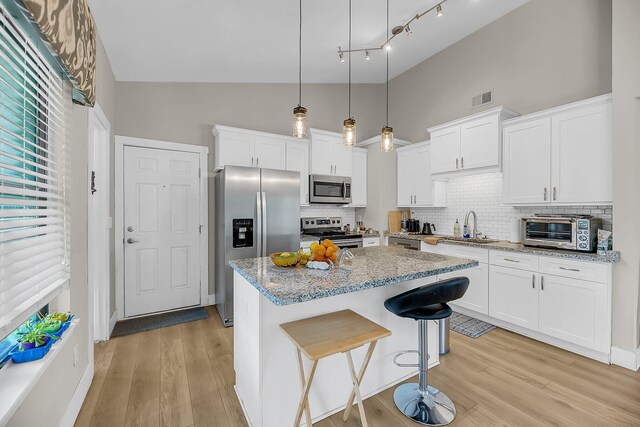 kitchen with visible vents, a toaster, a sink, backsplash, and stainless steel appliances