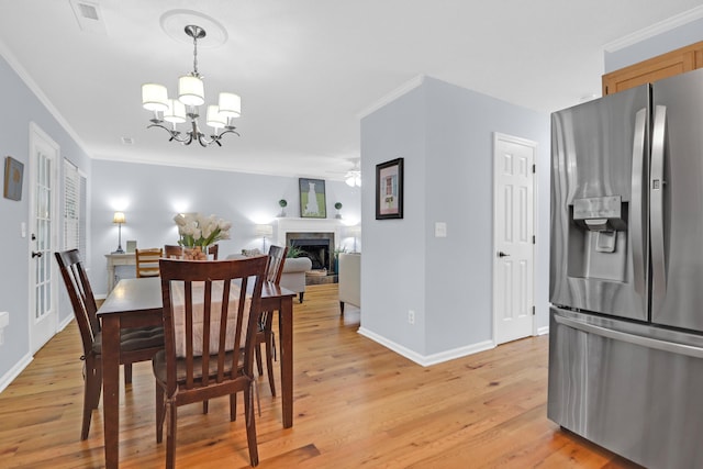 1394 Center Lake Dr, Mount Pleasant, SC 29464 - dining room with a chandelier, light wood finished floors, baseboards, ornamental molding, and a fireplace with raised hearth