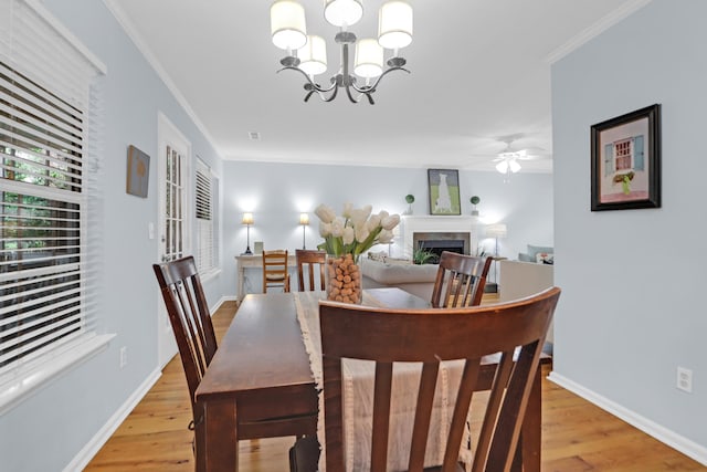 1394 Center Lake Dr, Mount Pleasant, SC 29464 - dining room with light wood-style floors, a fireplace, a chandelier, a ceiling fan, and crown molding