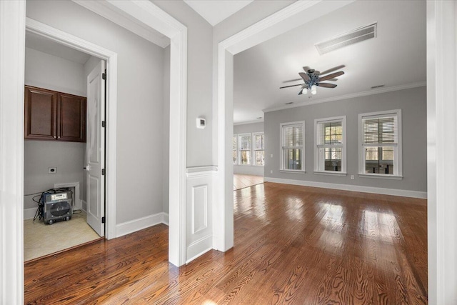 unfurnished living room with ornamental molding, wood finished floors, visible vents, and baseboards